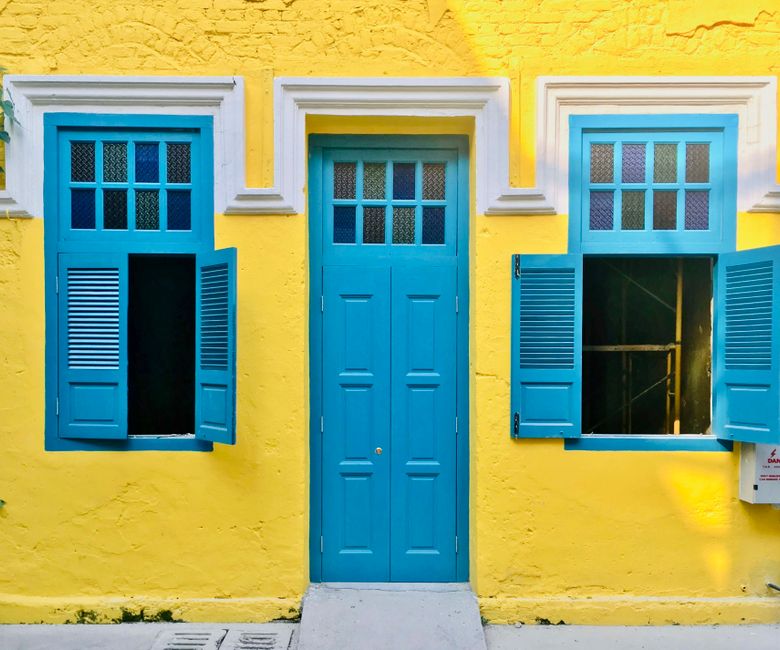 Colorful yellow house facade with striking blue door and windows.